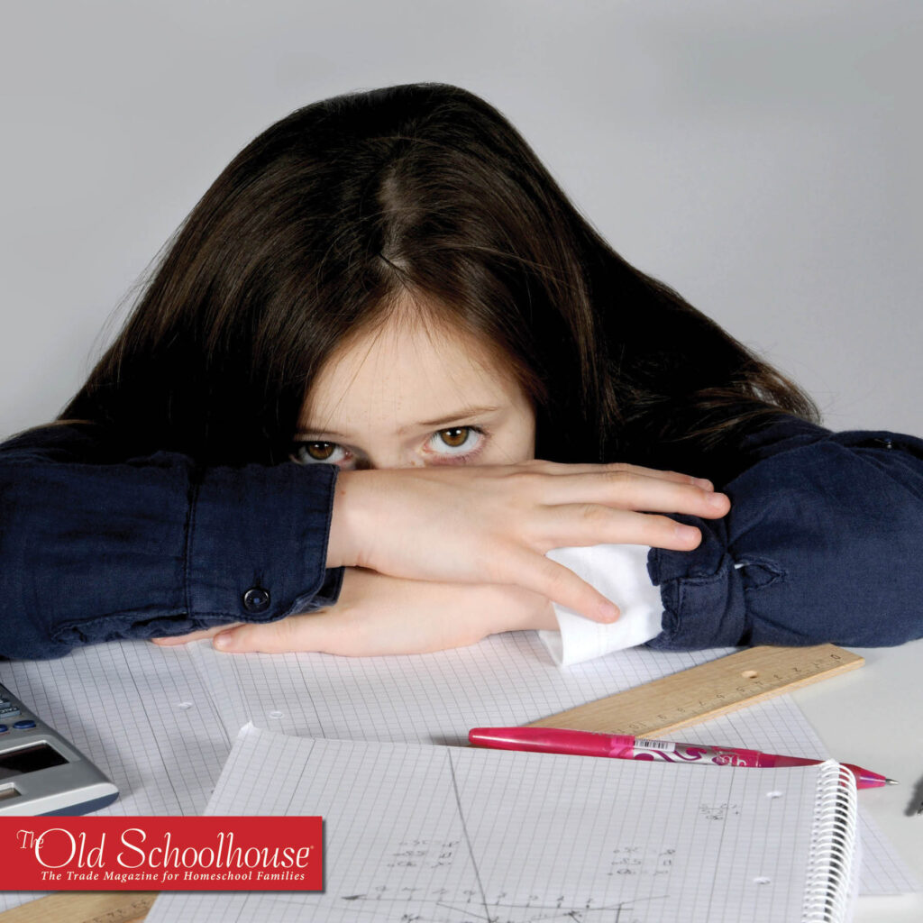 a young child with her head laying behind folded arms on her math work